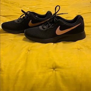 Black nikes with rose gold accent.